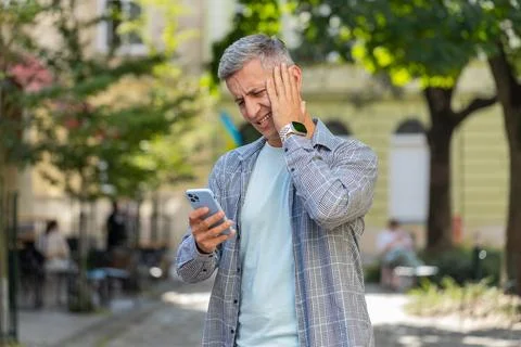 Mature man using smartphone typing browsing, loses becoming shocked sudden Stock Photos