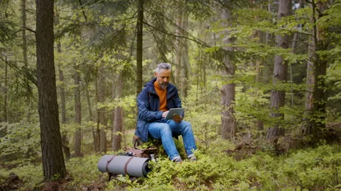 Mature man using tablet in forest in nature, outdoor office concept. Stock Footage 132837079