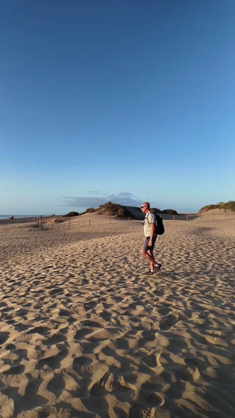 Mature man walking alone on a sandy beach Stock Footage 345839045