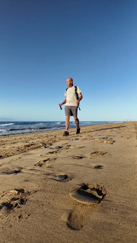 Mature man walking alone on a sandy beach Stock Footage 345839177