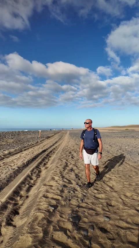 Mature man walking alone on a sandy beach path Stock Footage 346177540