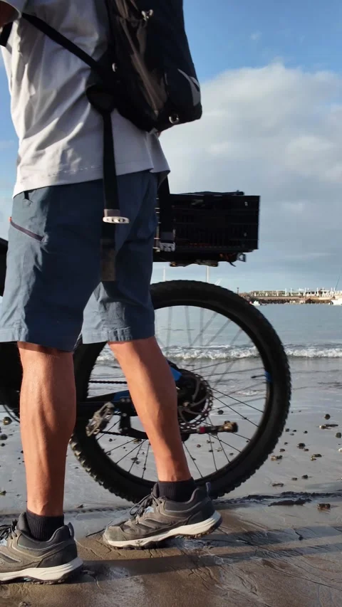 Mature man walking with an electric bicycle on a sandy beach Stock Footage 344816357