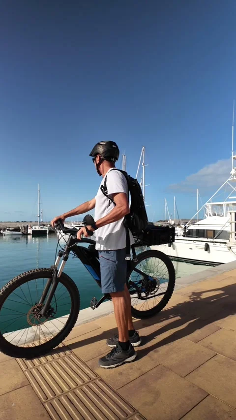 Mature man walking with his e-bike in a harbor Stock Footage 344816259