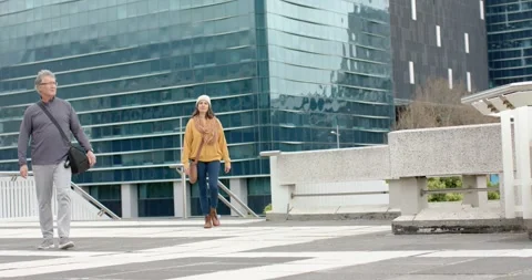 Mature man walking plaza checking wristwatch, mature woman descending steps Stock Footage 336058499