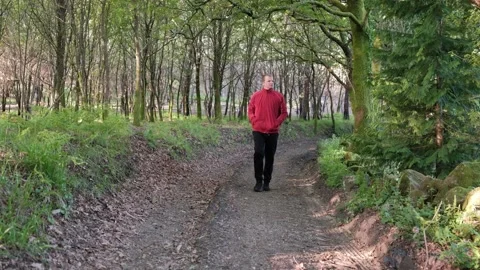 Mature man walking towards camera on forest path Stock Footage 344531161