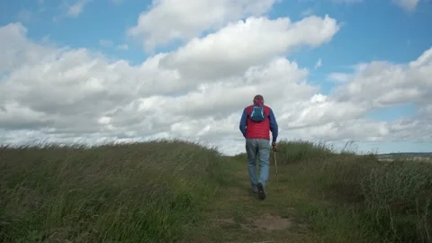 Mature Man walks down a path in English countryside with blue sky Stock Footage 201291849