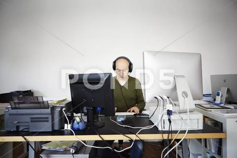 Mature Man Working In Creative Studio Wearing Headphones
