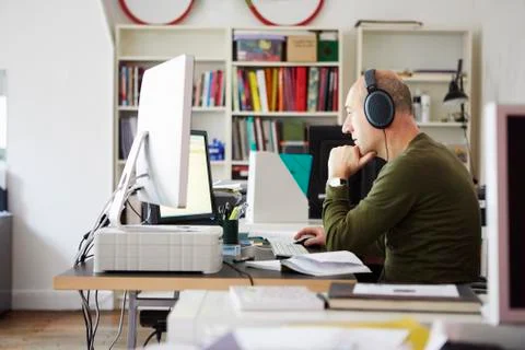 Mature man working in creative studio wearing headphones Foto stock