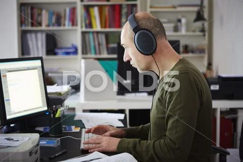 Mature Man Working In Creative Studio Wearing Headphones