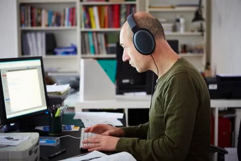 Mature man working in creative studio wearing headphones Stock Photos