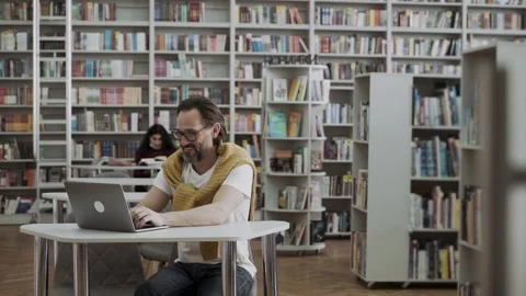 Mature man working or studying with laptop in the library Stock Footage 152855927