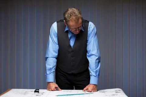 Mature manager, engineer or architect standing at a desk with a plan in a off Stock Photos