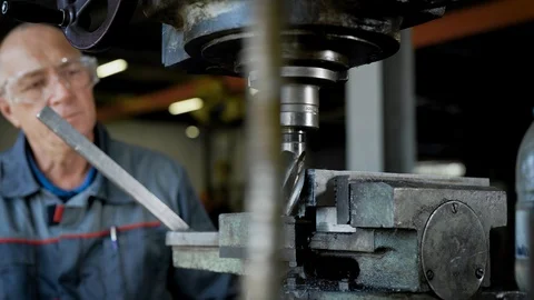 Mature master mechanic is controlling a work of industrial drilling machine in a Stock Footage 95088716