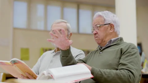 Mature men talking while reading textbooks in library Stock-Footage 232623204