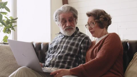 Mature mid age couple using laptop sit on sofa. White hair. New technology for Stock Footage 244118537