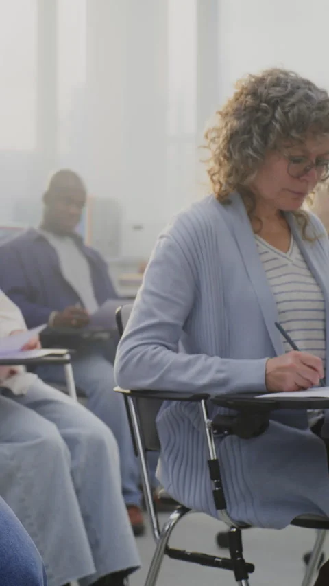 Mature Multicultural Students Attending Class, Taking Notes and Listening to Stock Footage 321252870