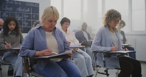 Mature Multicultural Students Attending Class, Taking Notes and Listening to Stock Footage 321254235