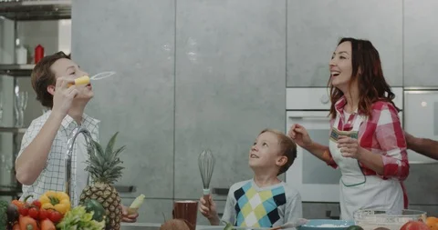 Mature parents playing with their two sons in a modern kitchen making bubbles. Stock Footage 101701822