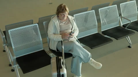 Mature passenger sits among rows of empty seats in airport terminal hall Stock Footage 343950867