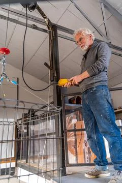 Mature potter is operating the freight elevator in his workshop Stock Photos