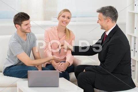 Mature Real Estate Agent Giving House Key To Young Happy Couple Stock Photos