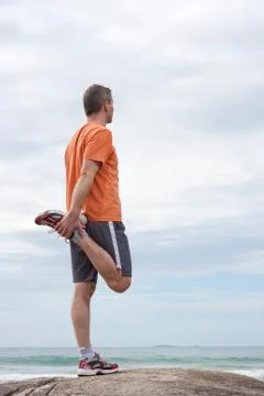 Mature runner doing exercises at a beach Фото