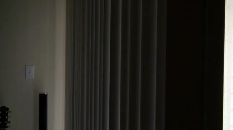 A mature scared woman peering through blinds Stock Footage