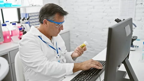 Mature scientist analyzing medication while using computer in laboratory 動画素材 267222655