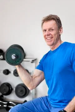 Mature smiling man doing work out in a fitness room - focus on the face and t Stock Photos