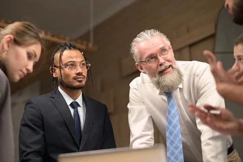 A mature solid gray-haired head of a firm discusses tasks with his subordinat Stock Photos