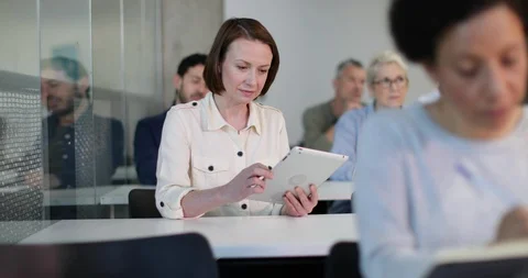 Mature student taking notes on digital tablet in a lecture Video stock 86508868