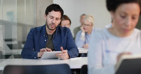 Mature student taking notes on digital tablet in a lecture Video stock 86513559