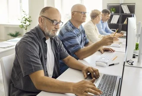 Mature students learning computer skills in workplace training lab with 写真素材