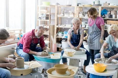 Mature students using pottery wheels in studio Stock Photos