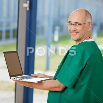 Mature surgeon holding laptop Stock Photos