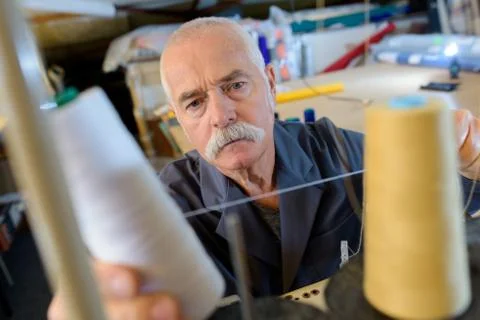 Mature tailor with spool of thread Stock Photos