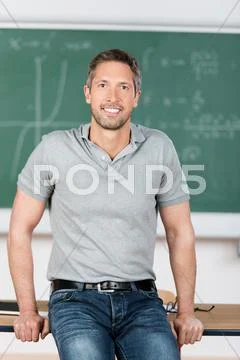 Mature teacher leaning on bench in classroom Stock Photos