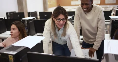 Mature teacher working with students inside computer classroom at school Stock Footage 168623147