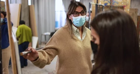 Mature teacher working with students while wearing safety masks Stock Footage 168623419