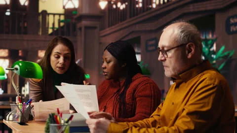 Mature team of performers rehearsing script dialogue together in a library Stock Footage 313308337