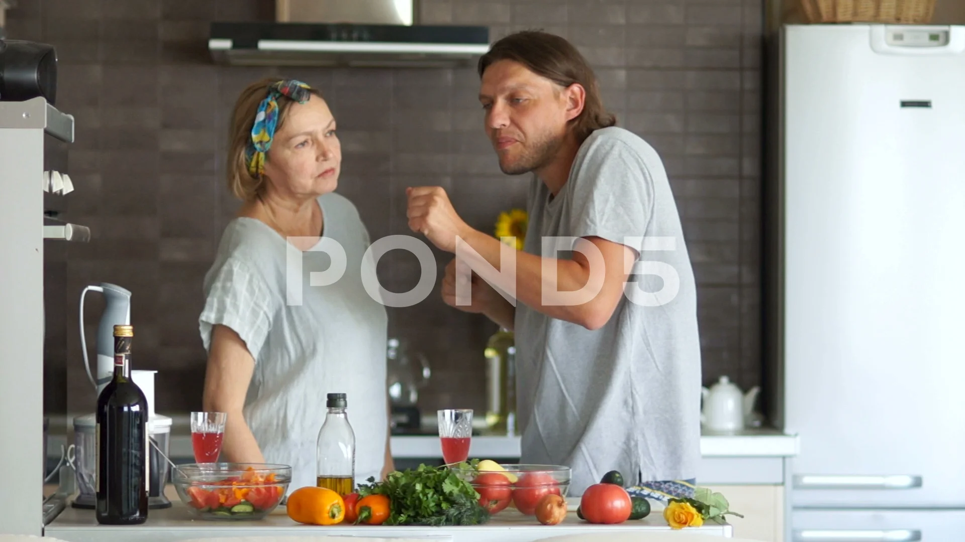 Mature woman and young man dancing and flirting in the kitchen