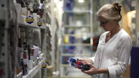 Mature woman comparing door knobs in a big box hardware store shopping for home Video stock 275949543