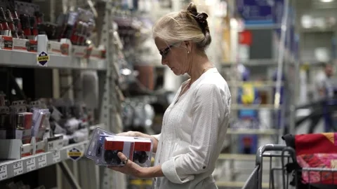 Mature woman comparing door knobs in a big box hardware store shopping for home 動画素材 276547454