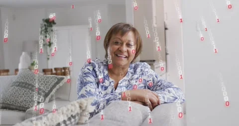 Mature woman leaning on sofa, binary overlay appearing and passing, evoking Stock Footage 320586333
