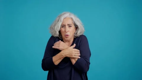 Mature woman looking at camera while embracing herself expressing coldness Video stock 229548722