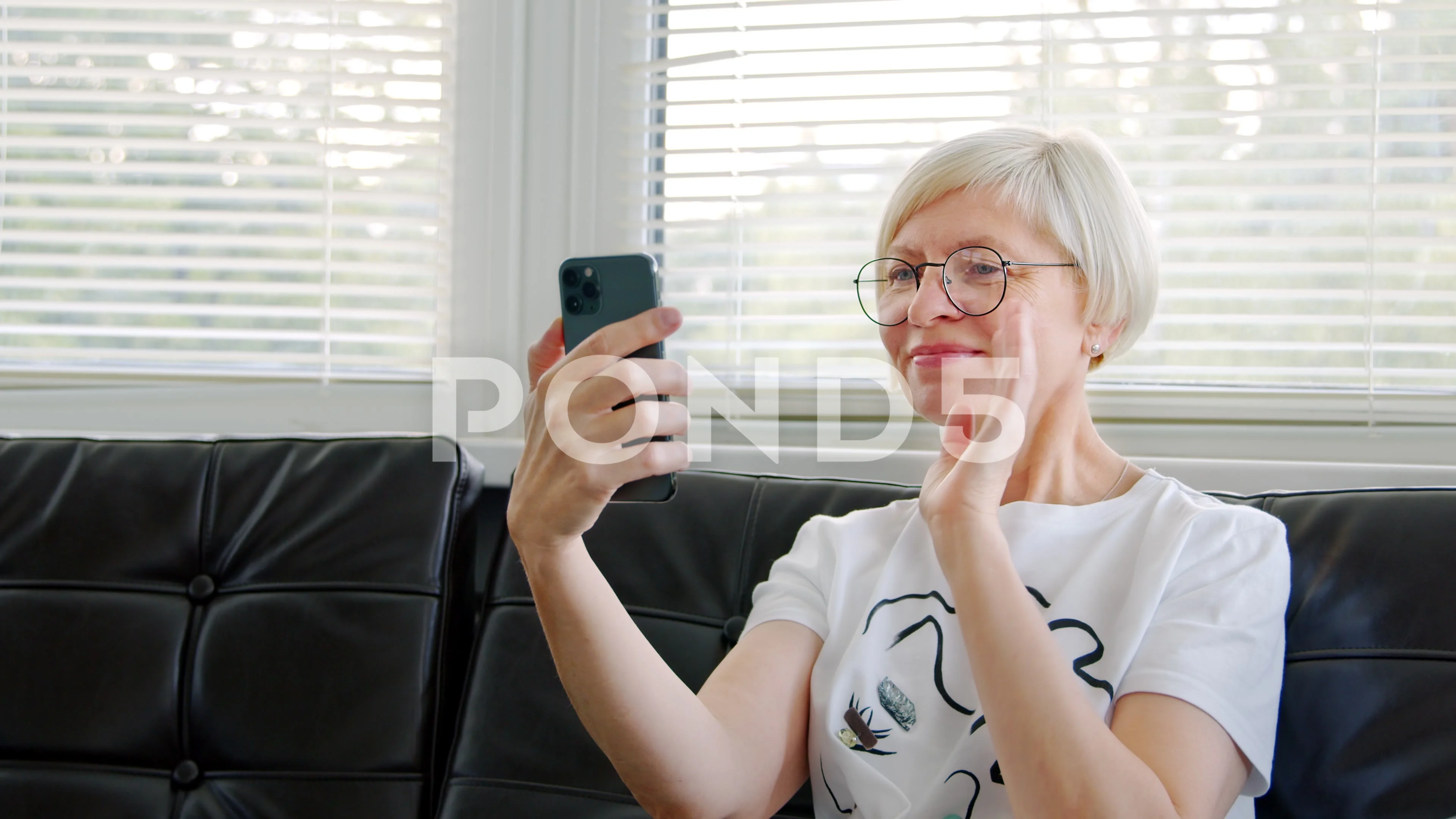 Mature woman making video call online at home using smart phone. image