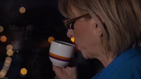 Mature woman observes the city light from her window, tea 스톡 동영상 59129396