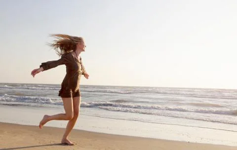 Mature woman running along beach Stock Photos