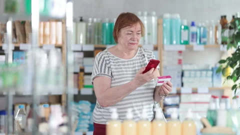 Mature woman scans code on package of paracetamol pills to check the expiration Stock Footage 310531863