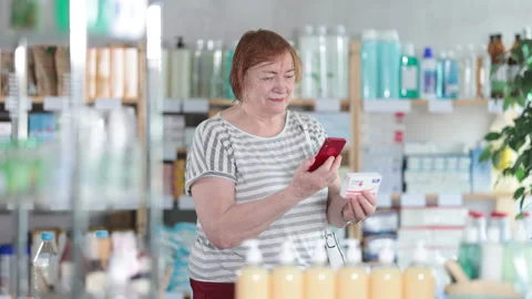 Mature woman scans code on package of paracetamol pills to check the expiration Stock Footage 313099322